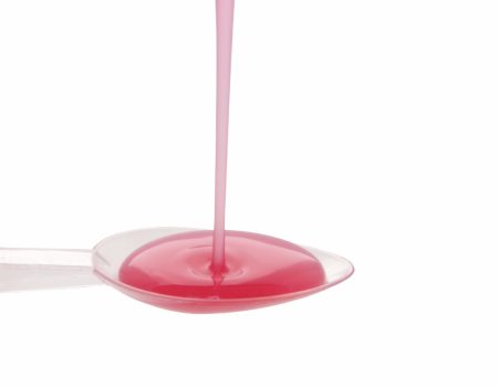 Pink childs medicine measured into a spoon